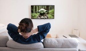 behind of asian young woman watching white screen TV on the sofa